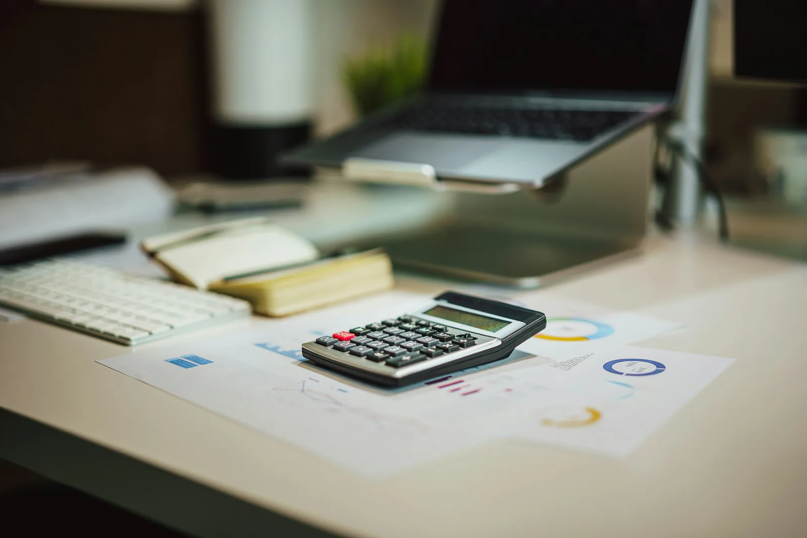 A calculator on financial reports beside a laptop